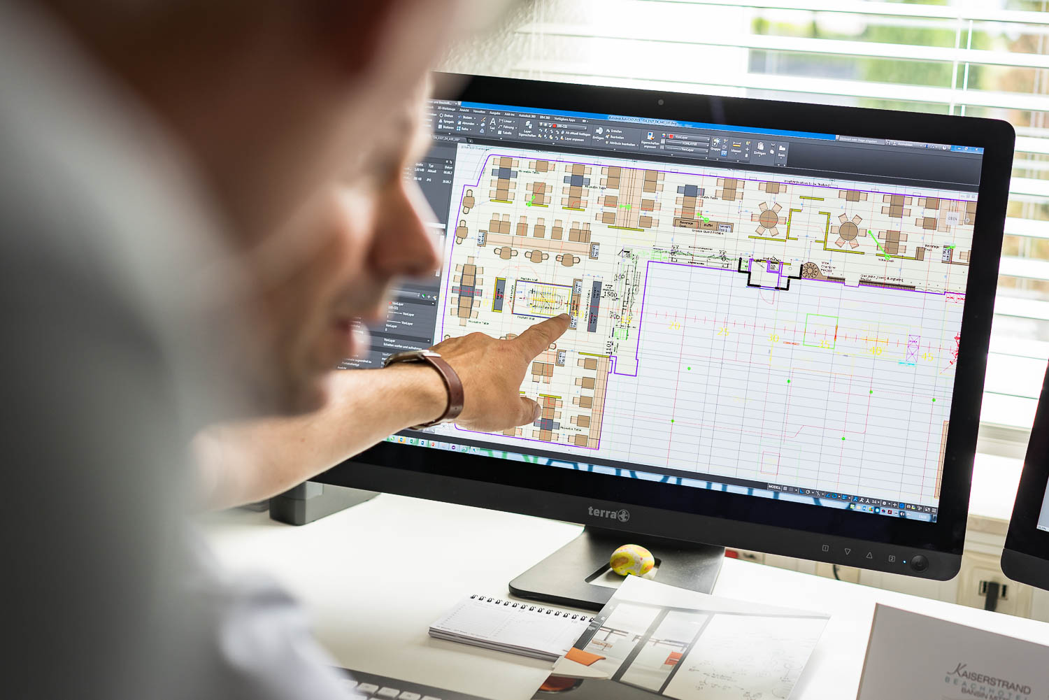 Architekt zeigt auf digitale Bauplanung am Computerbildschirm