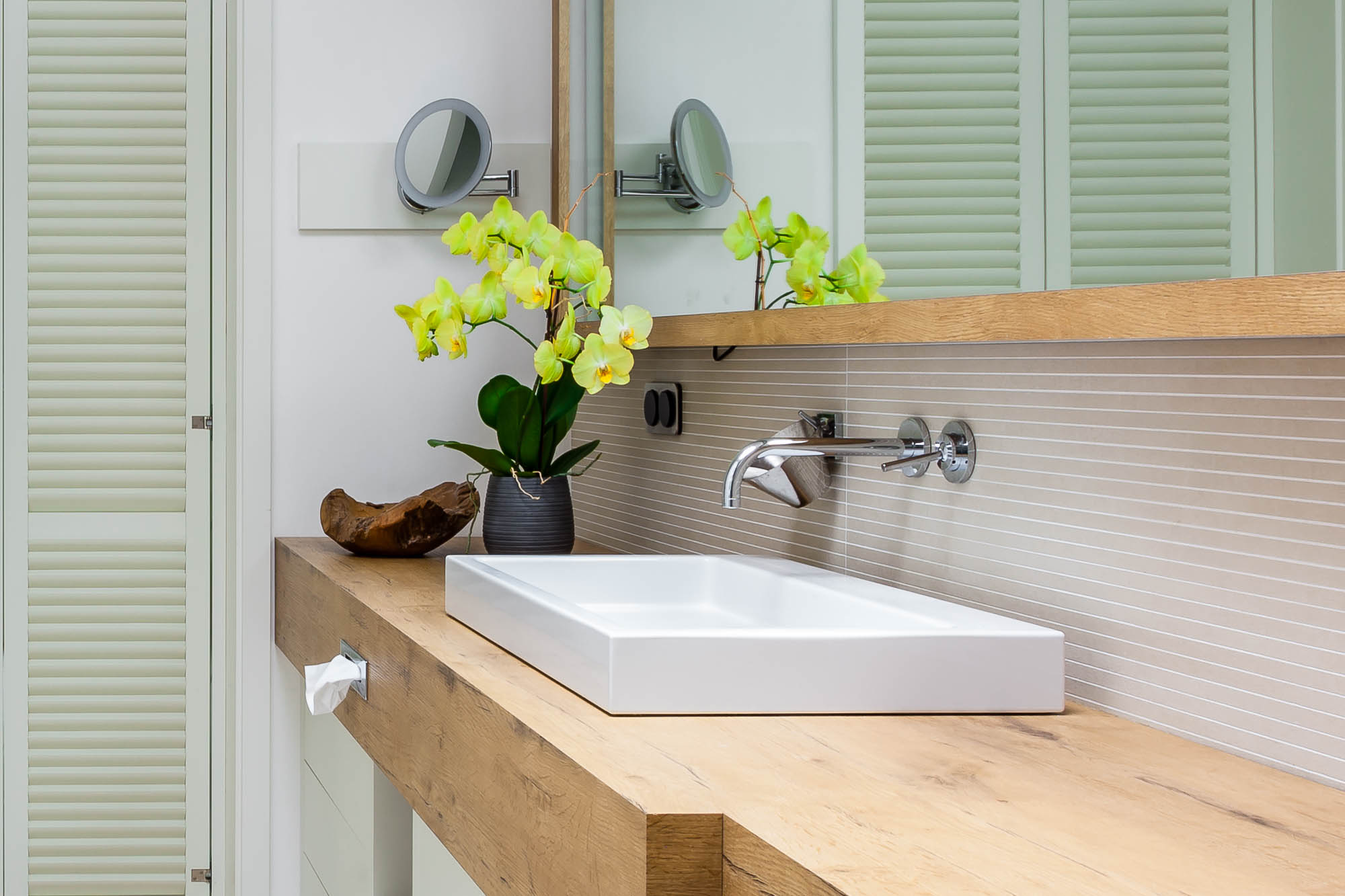 Waschbecken mit Holzkonsole und frischen Blumen