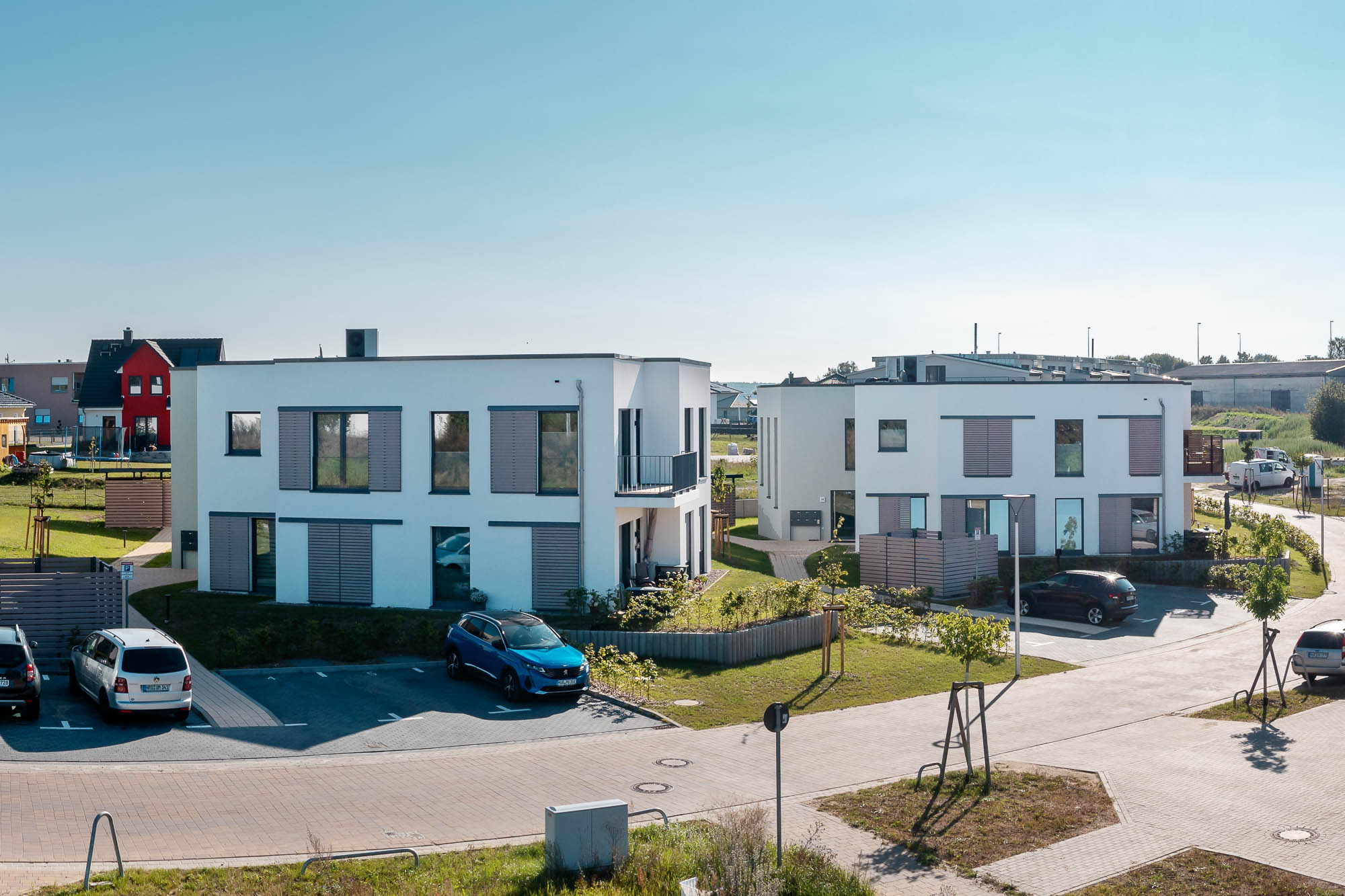 Gesamtansicht der Wohnhäuser mit Parkplatz und Begrünung