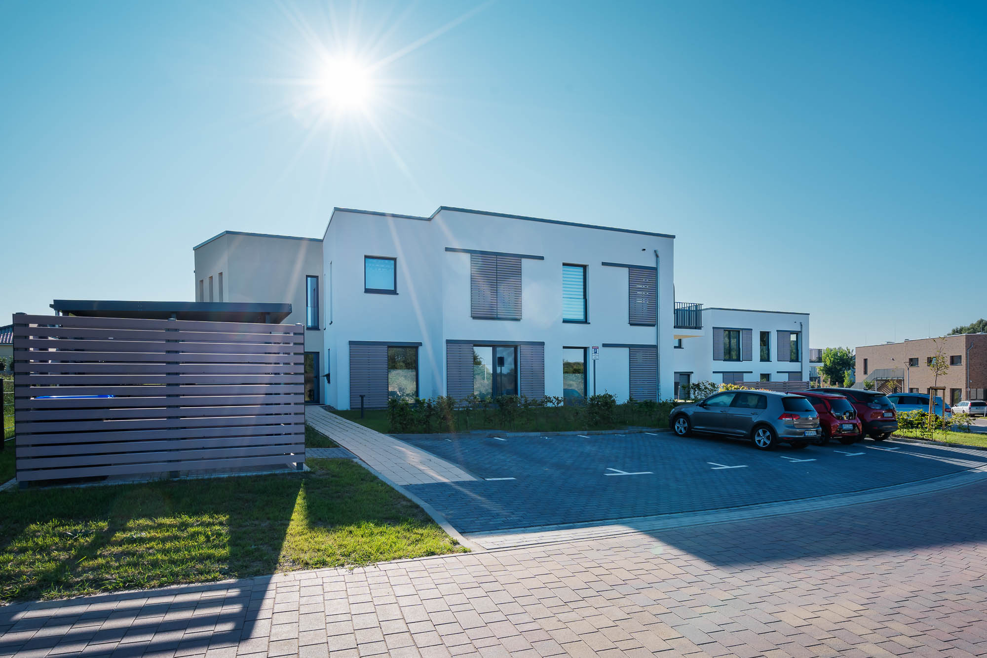 Neubauprojekt mit gepflegter Zufahrt und Sonnenspiegelung