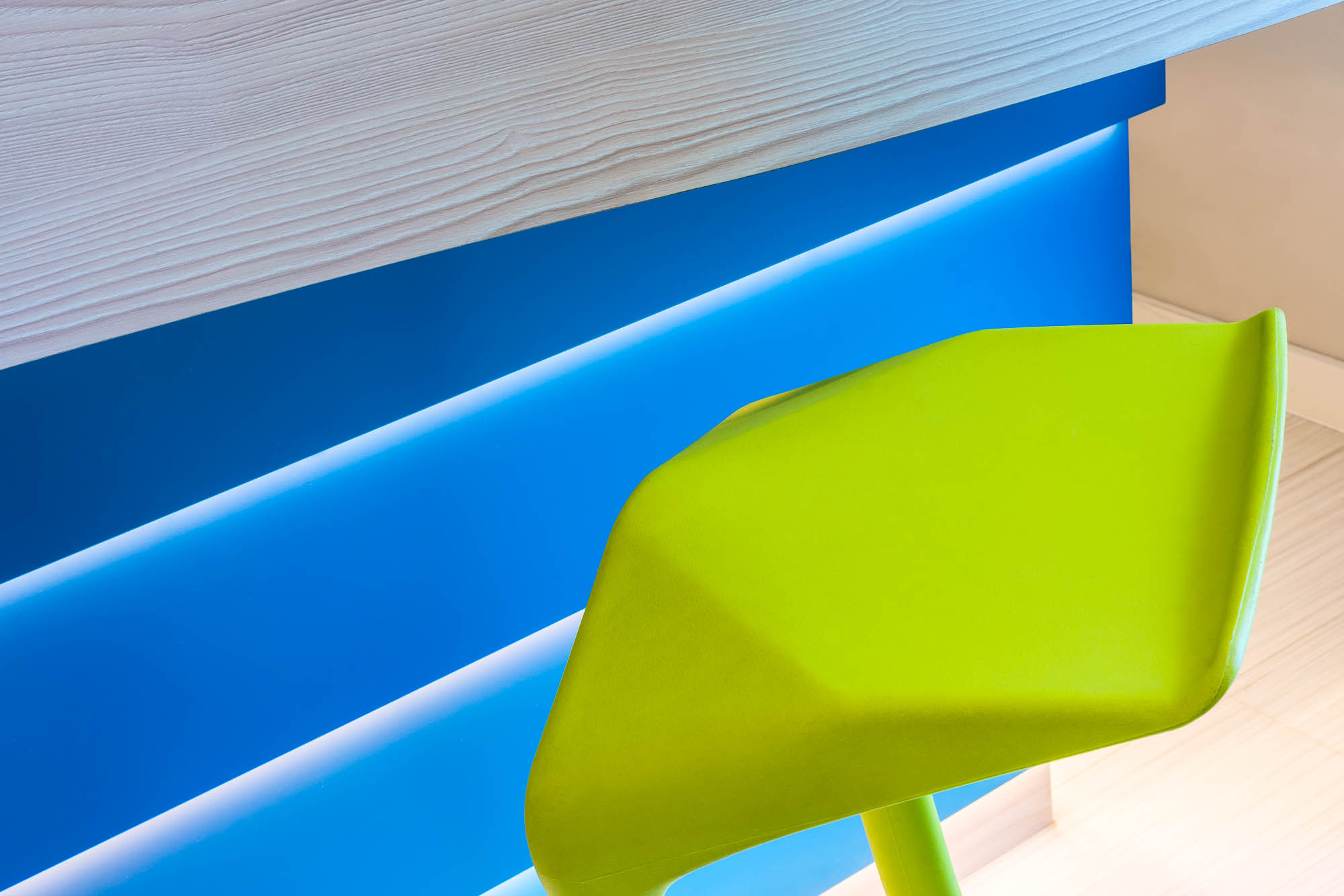 Detailaufnahme einer blauen Theke mit grünem Barstuhl in modernem Farbkontrast.