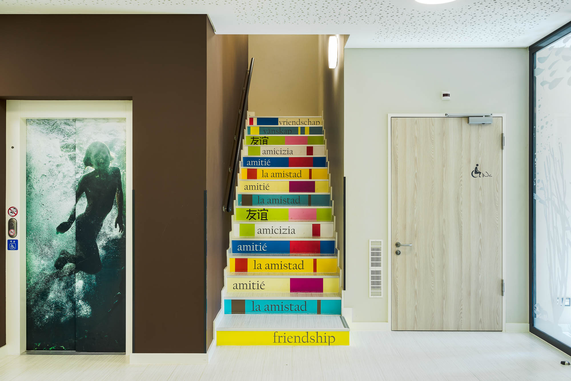 Treppenhaus mit bunten Stufen und hellen Wänden