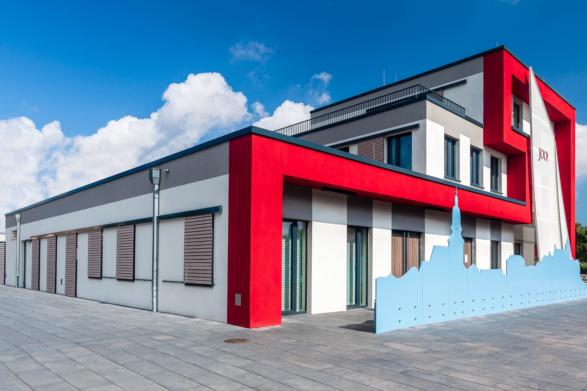 Modernes Gebäude mit roter Fassade und großen Fenstern.