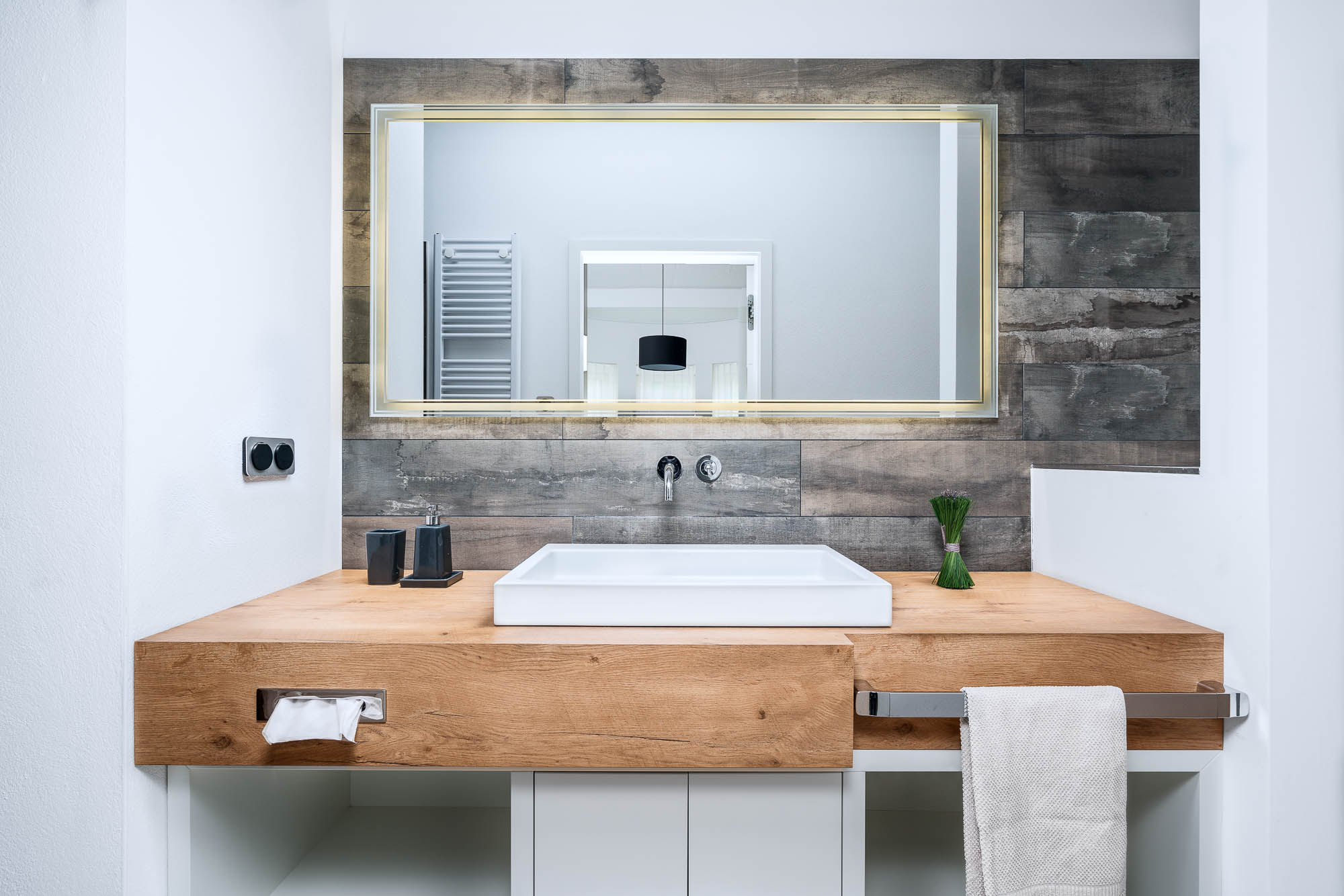 Badezimmer mit Holzwaschtisch und großem Spiegel