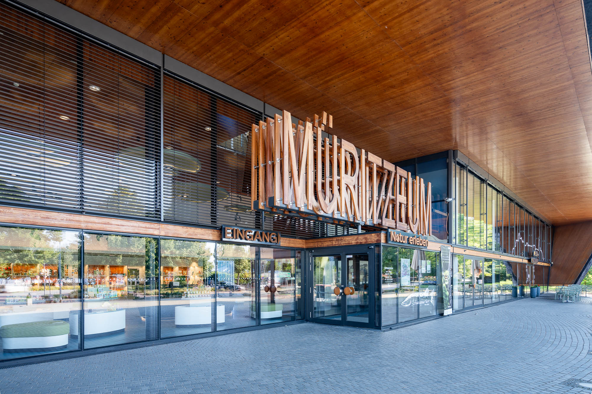 Glasfassade mit Holzverkleidung und überhängendem Dach