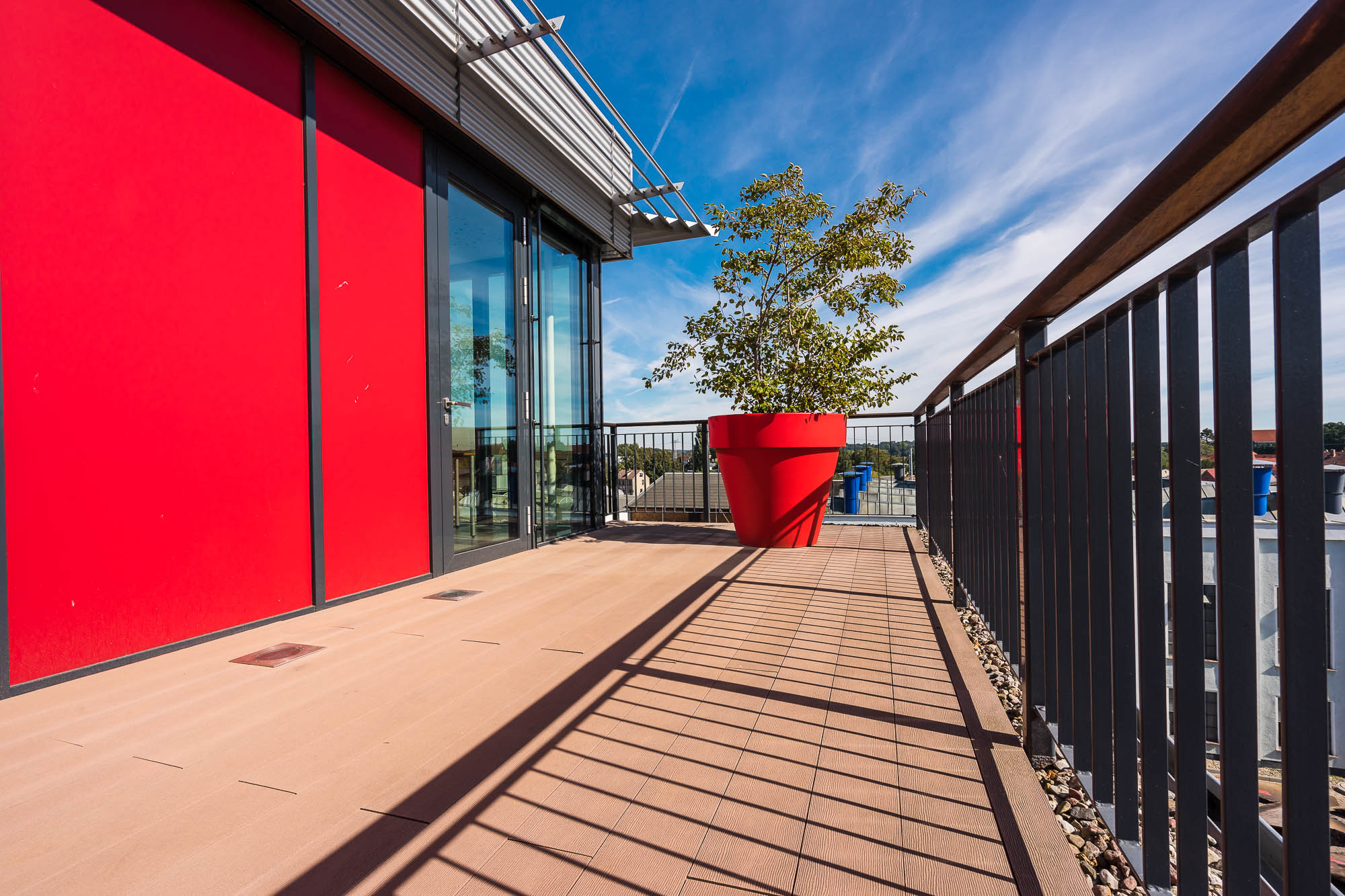Balkon mit roter Fassade und Pflanzkübel