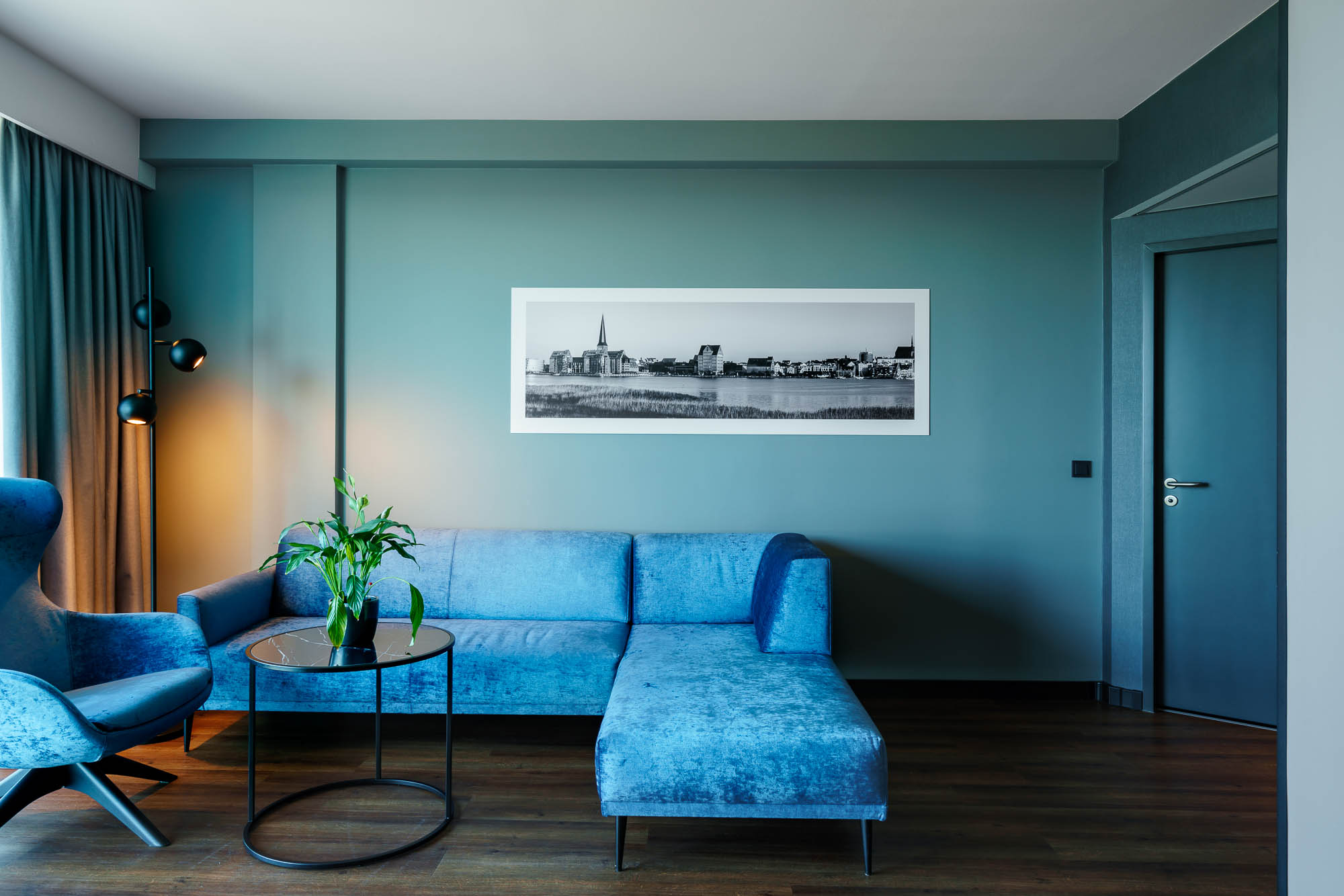 Wohnbereich mit blauer Couch und Wandbild