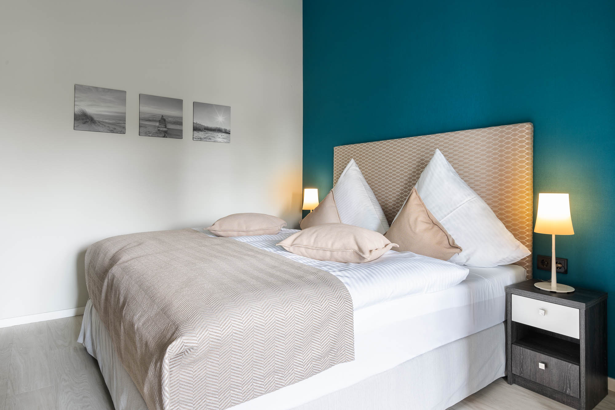 Schlafzimmer mit türkisfarbener Akzentwand und Doppelbett