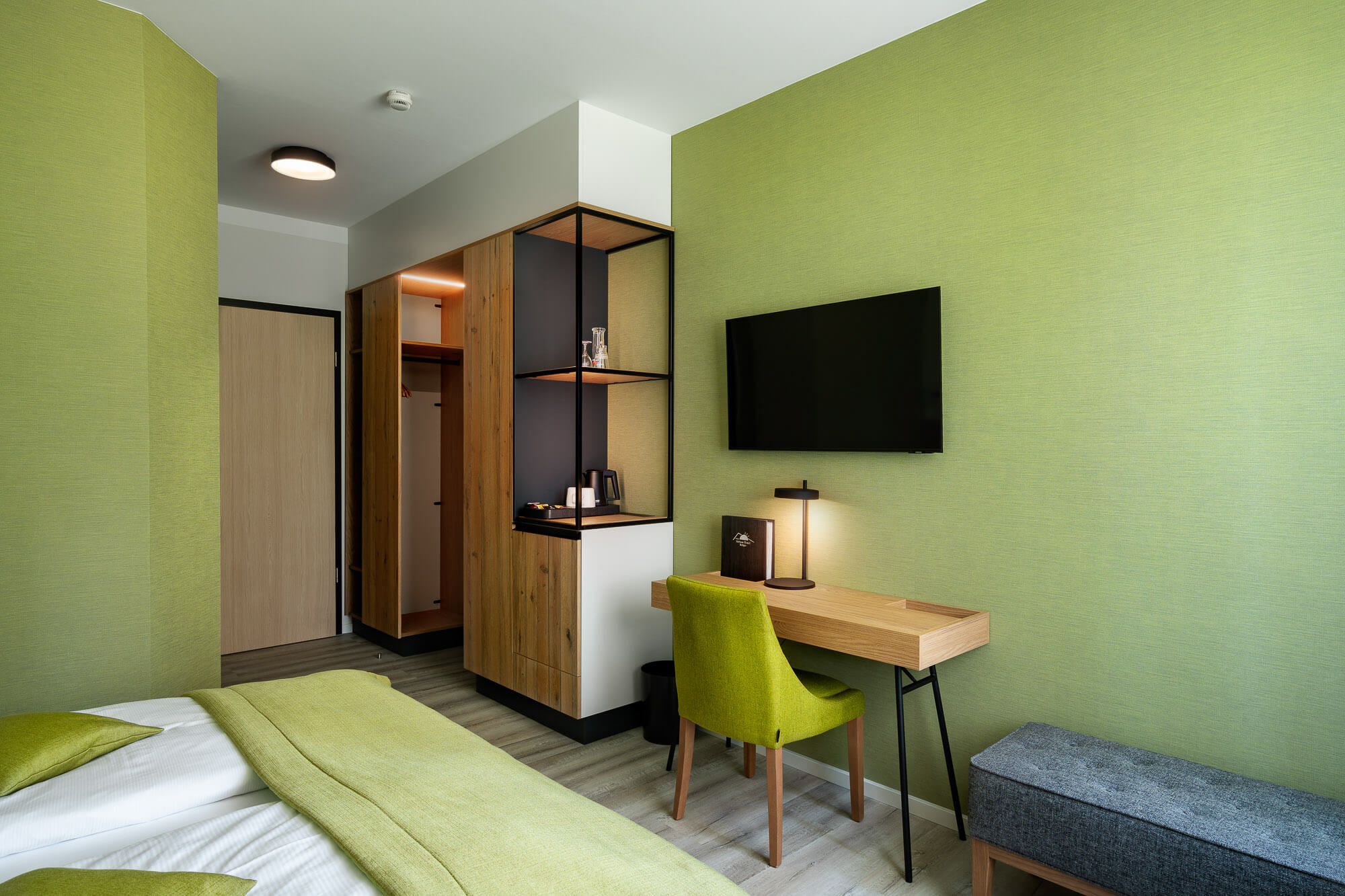 Hotelzimmer mit Schreibtisch und grünem Farbkonzept