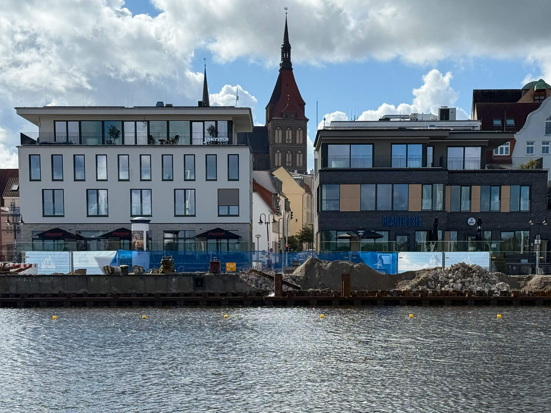 Moderne Hafenbebauung mit historischem Kirchturm im Hintergrund